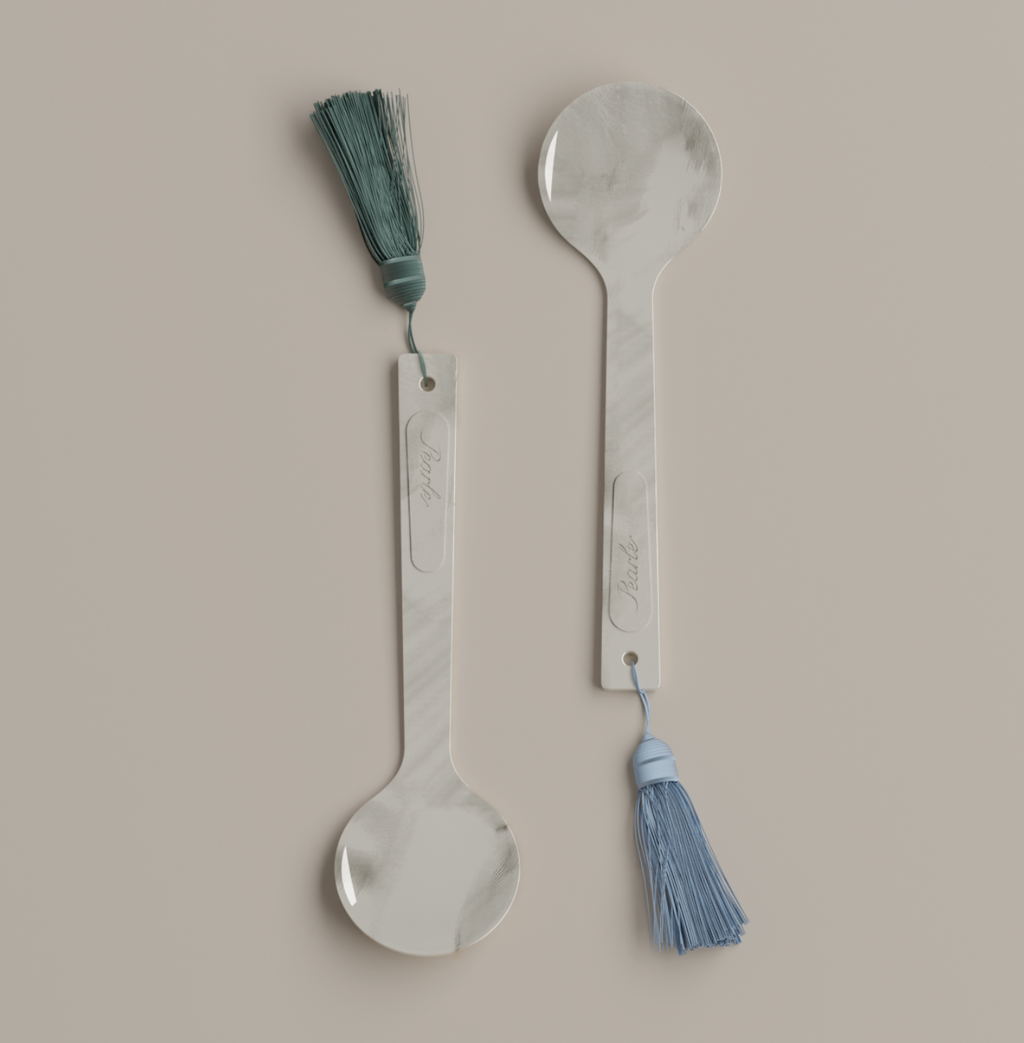 Two mother of pearl caviar spoons with tassels on a beige background